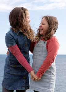 2 Girls holding hands by sea